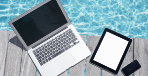 computer, tablet, and phone on deck next to pool